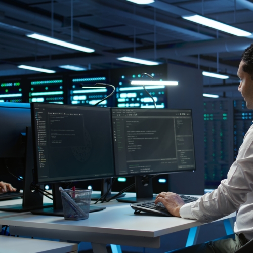 Engineers in high tech data center establishment installing software on computer, troubleshooting issues. Team of IT specialists in server room establishing performance benchmarks